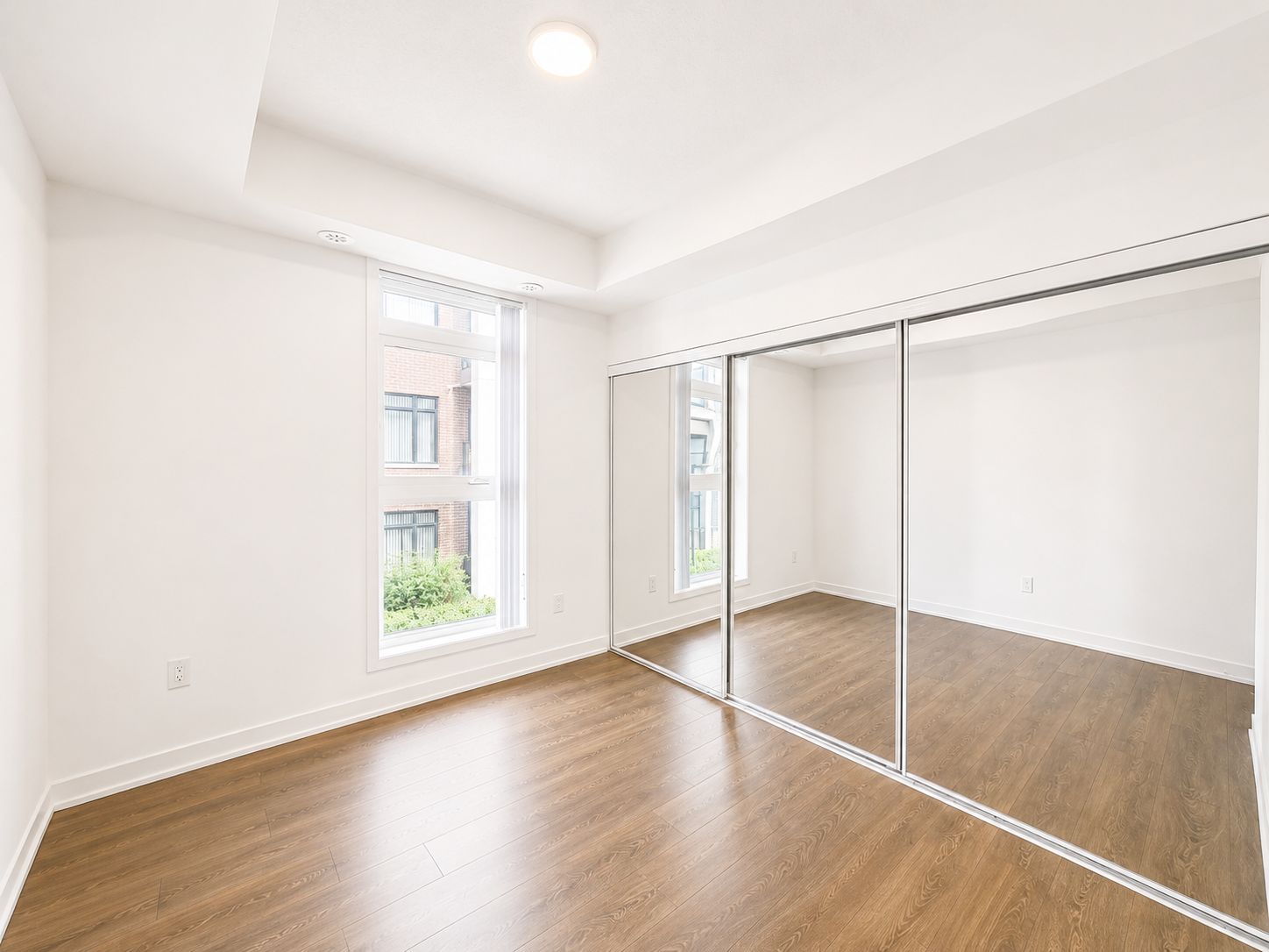 Second bedroom with mirrored closet and natural light